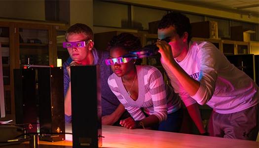 三个学生在黑暗的教室里观看激光